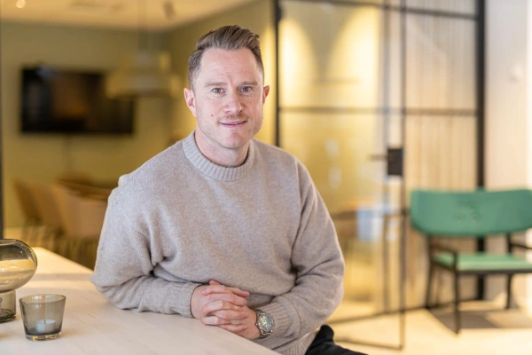 Porträtt av Mikael Thelin sittandes vid ett bord inomhus.